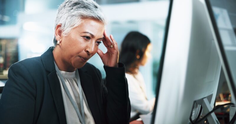 Mature woman, headache and stress with computer for mistake, difficult task or overworked at office. Female person, analyst or working late with migraine at night for fatigue, pressure or deadline