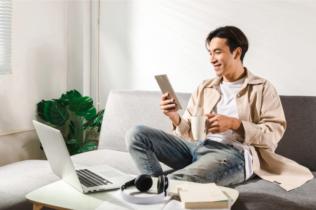 Happy smiling Asian student sits and relaxes on a couch