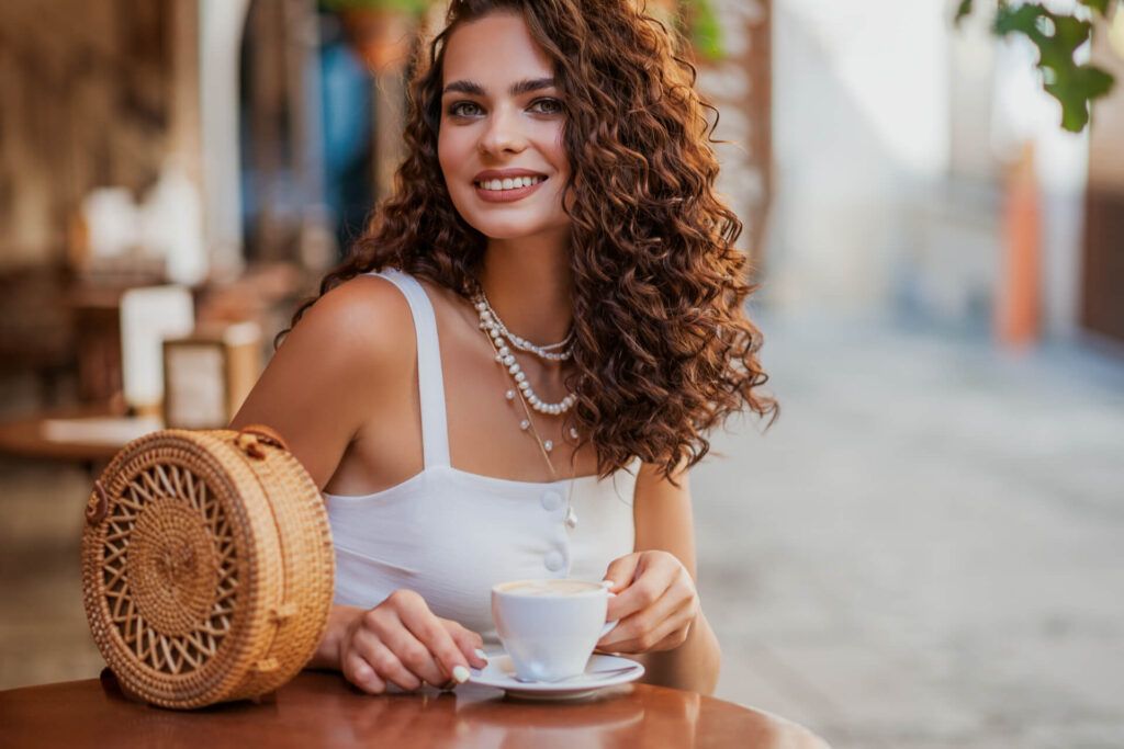 Happy smiling curly brunette woman drinking coffe