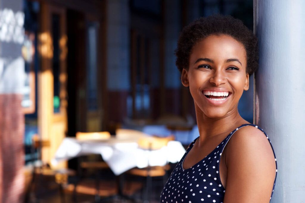 Side portrait of smiling young black woman standing outside