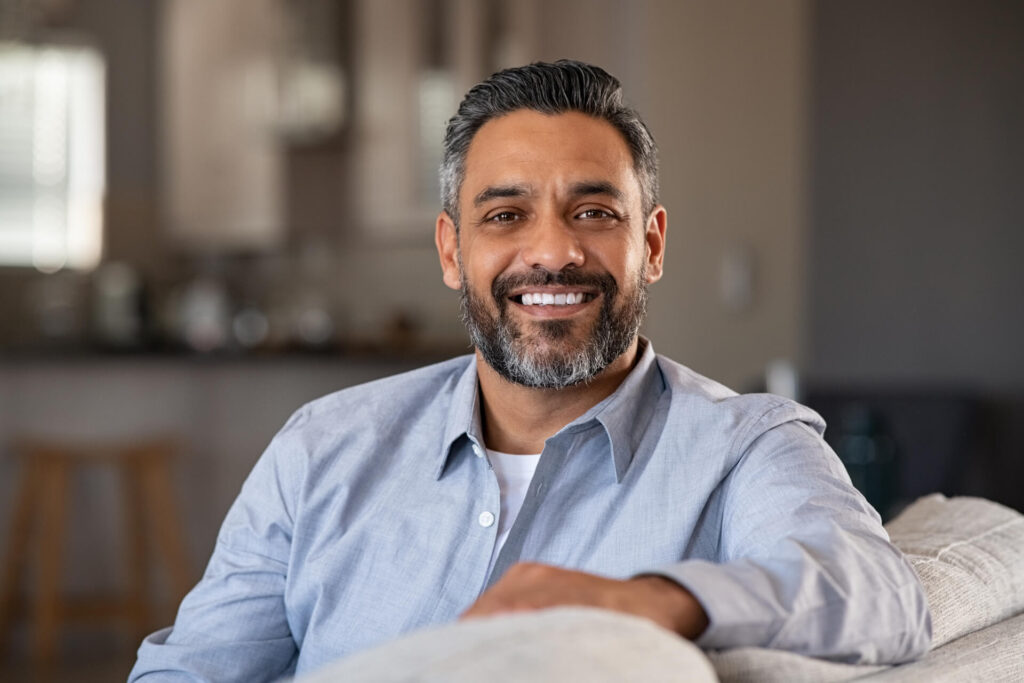 Portrait of happy mid adult man sitting on sofa at home