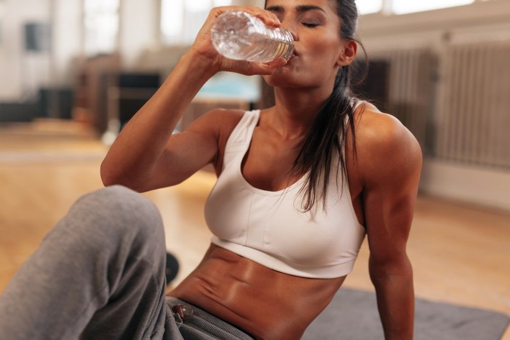 Fitness woman drinking water from bottle.