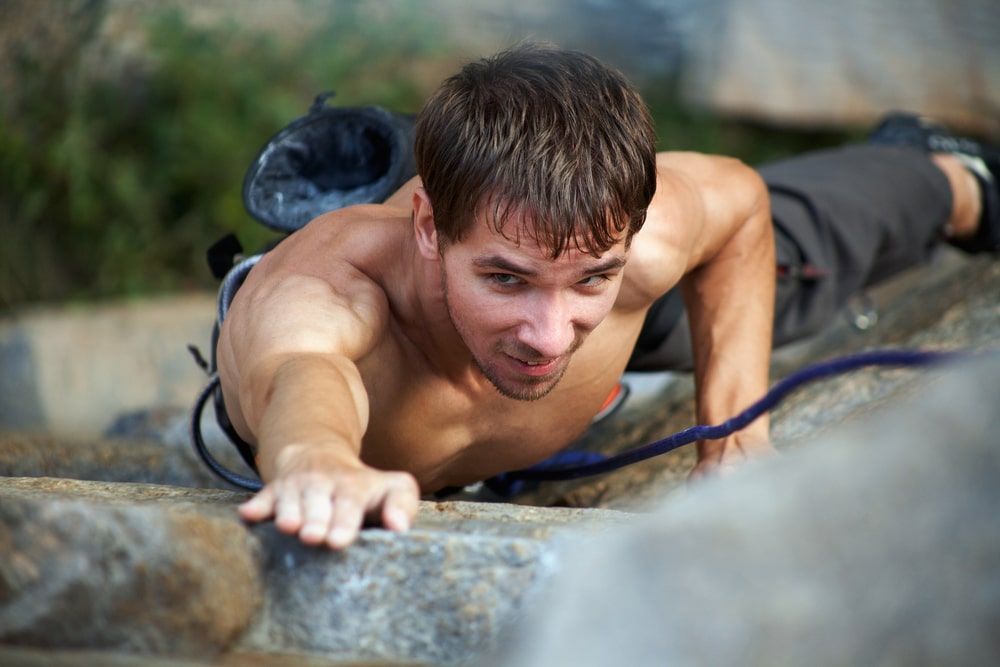 young man climbing up the rock