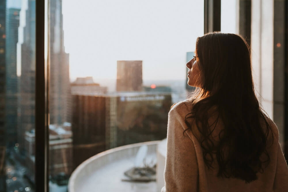 Young woman sitting at window enjoying the city skyline