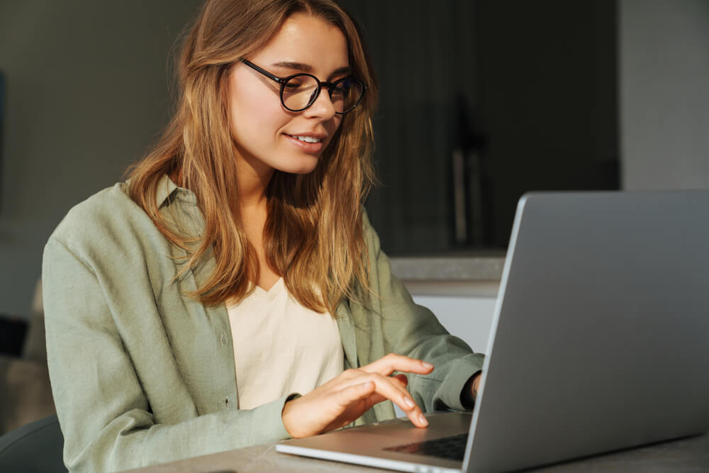 Pleased beautiful woman working with laptop while sitting at home