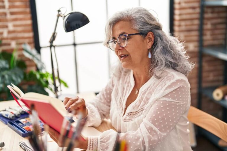 Middle age woman artist reading book at art studio