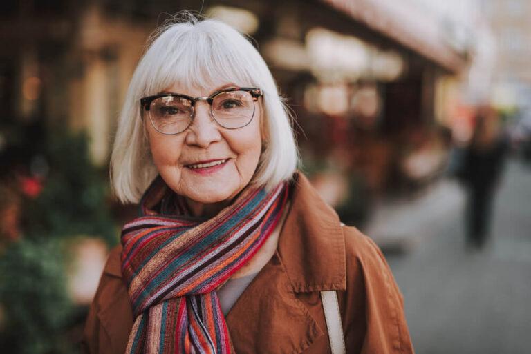 Portrait of stylish old lady in coat looking at camera and smiling