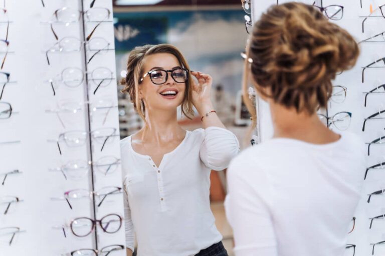 Girl is standing with set of glasses in background in optical shop