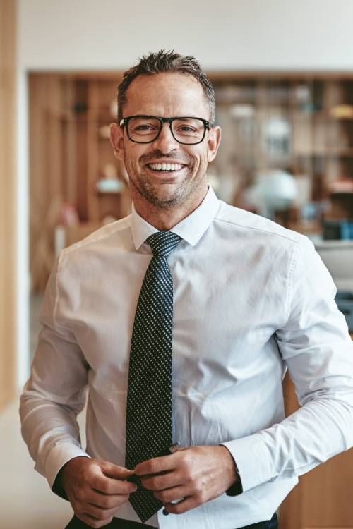 Man with glasses and tie smiling