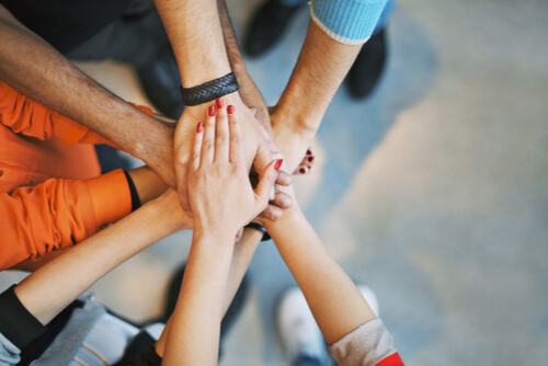 Multiethnic group of young people putting their hands on top of each other