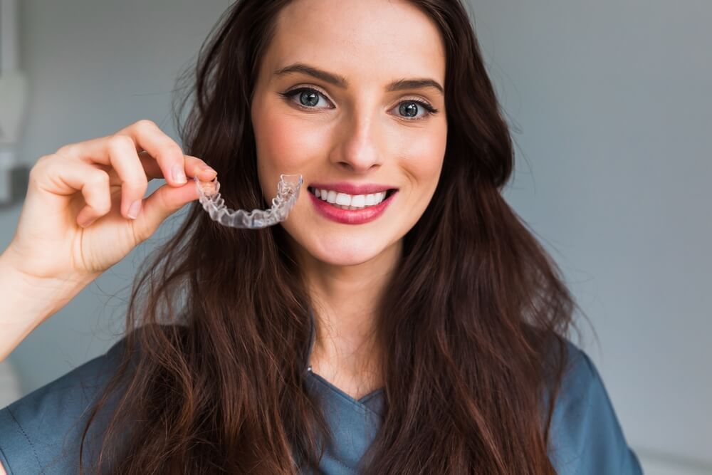 Young beautiful woman holding dental aligner orthodontic