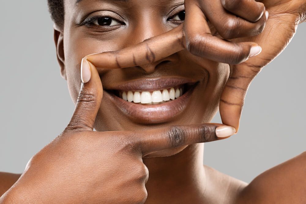 Beautiful woman framing her perfect white teeth with fingers