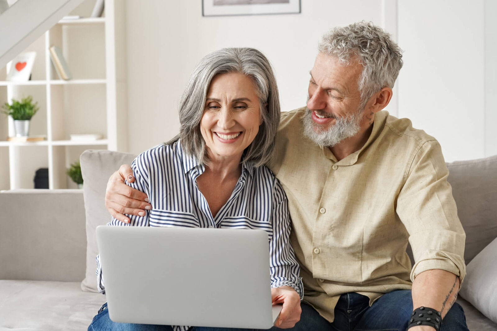 Happy mature mid age couple using laptop sit on sofa