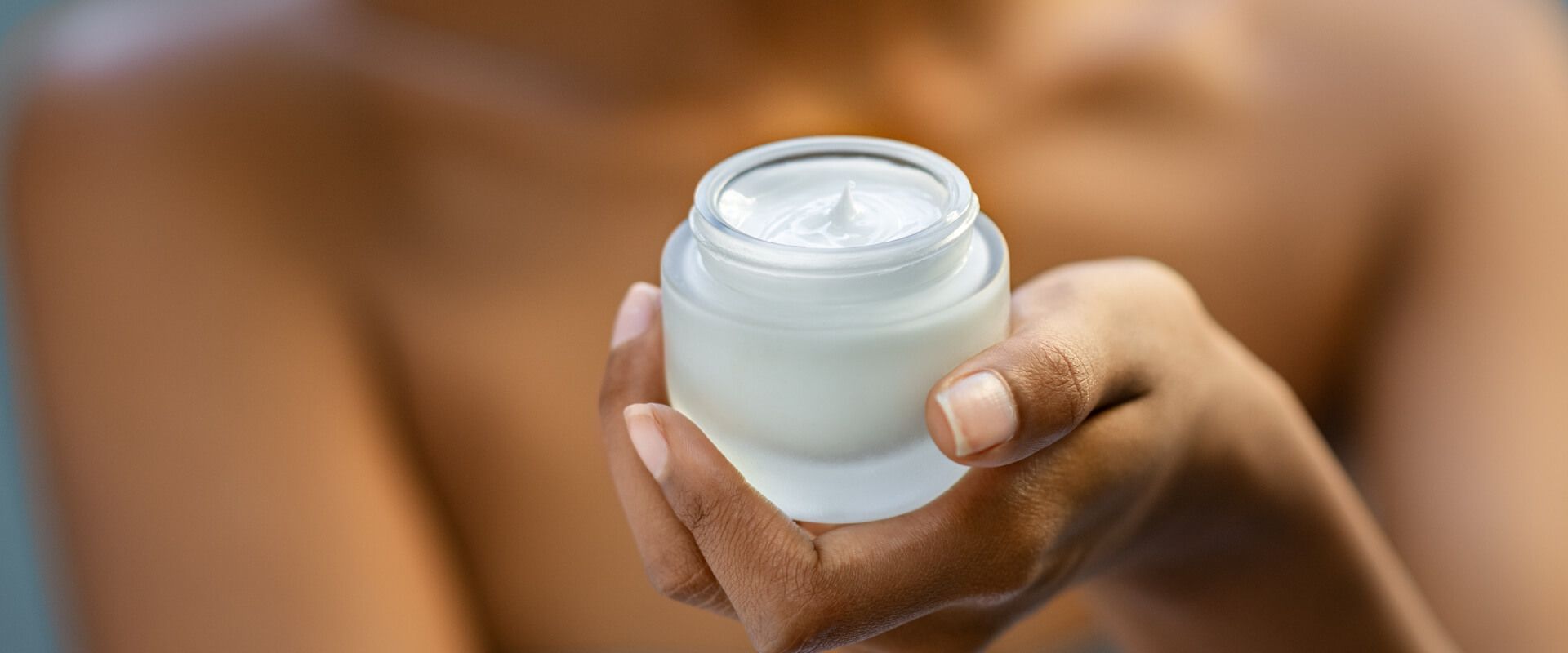 Closeup of African woman holding moisturizer cream