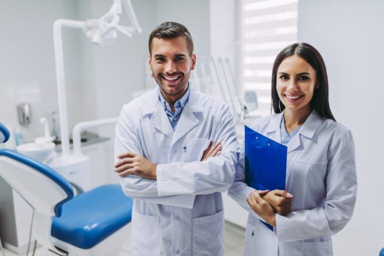 Two smiling doctors standing at workplace in modern dental clinic