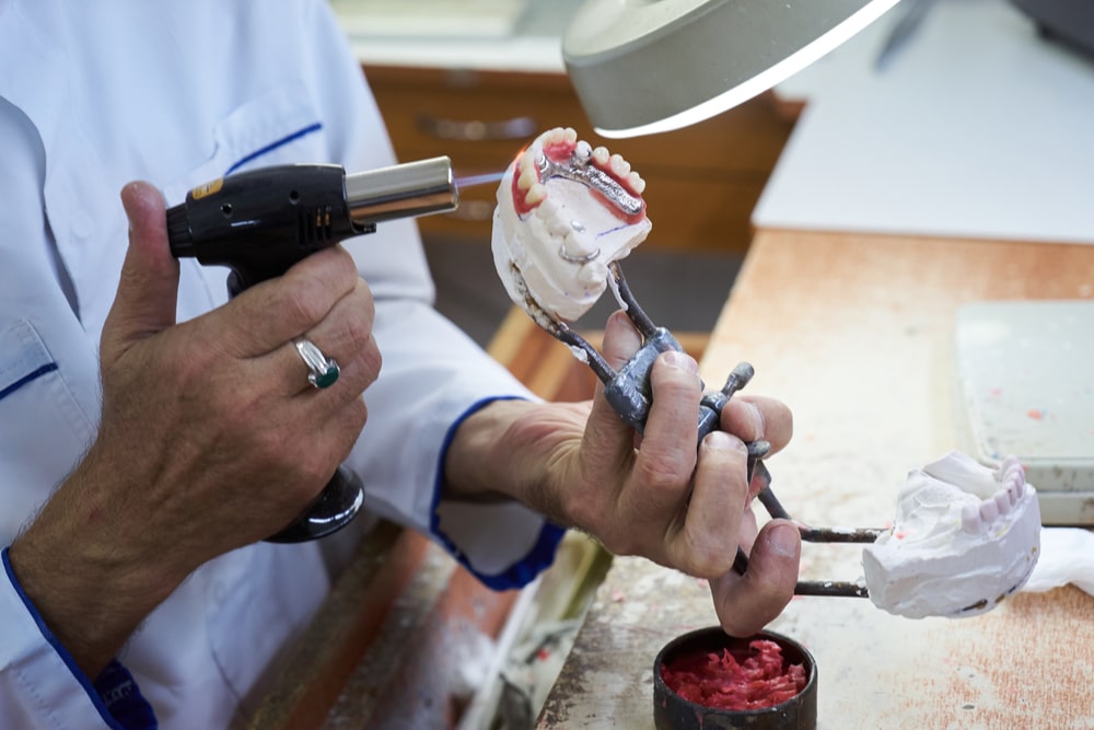 Dental technician working with articulator in dental laboratory