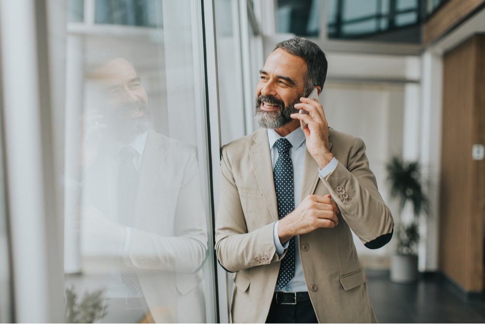 Handsome mature businessman with mobile phone in the office