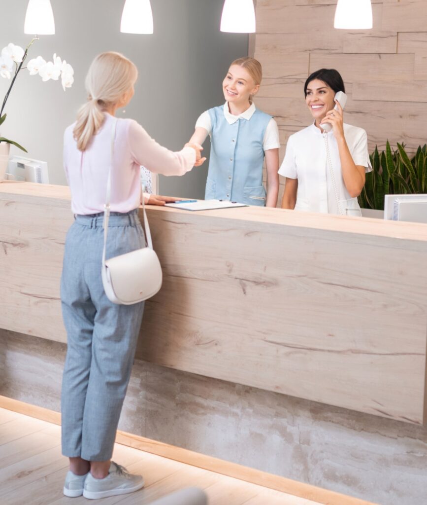 Grateful patient. Woman standing at the reception of dental clinic shaking hands with her dentist