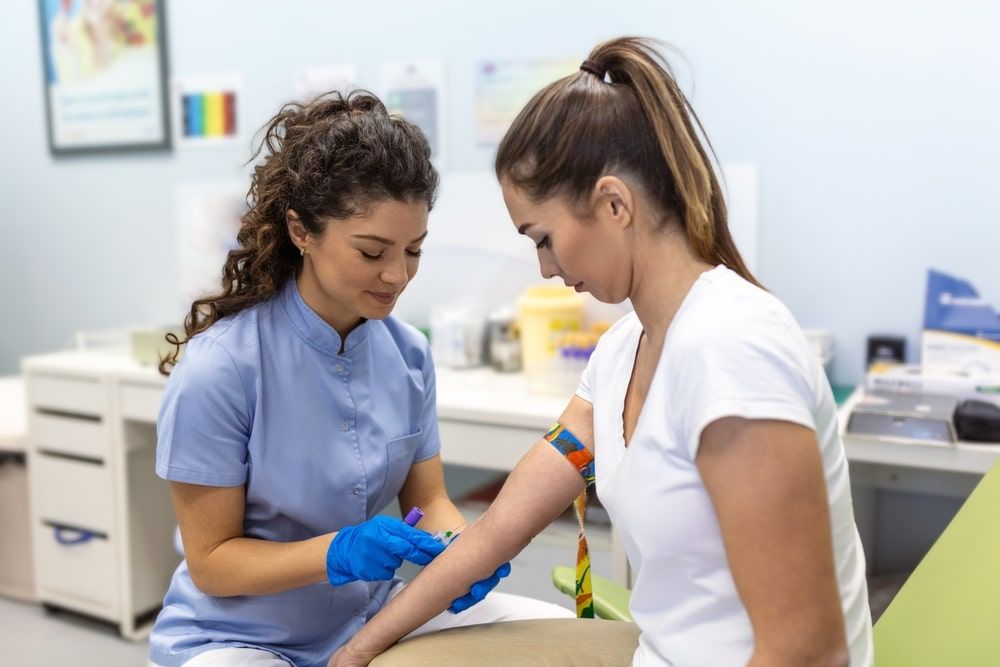Preparation for blood test with pretty young woman by female doctor