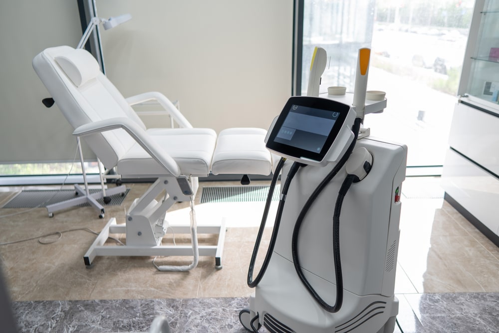 Beautician office with white couch and photorejuvenation machine.