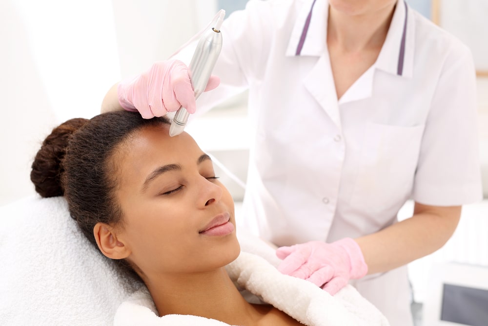 Beautician performs a needle mesotherapy treatment on a woman's face