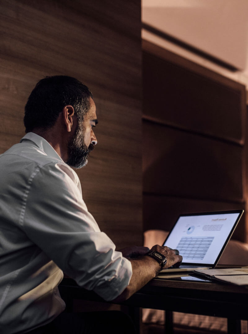 Elegant businessman sitting in hotel room and working late at night.