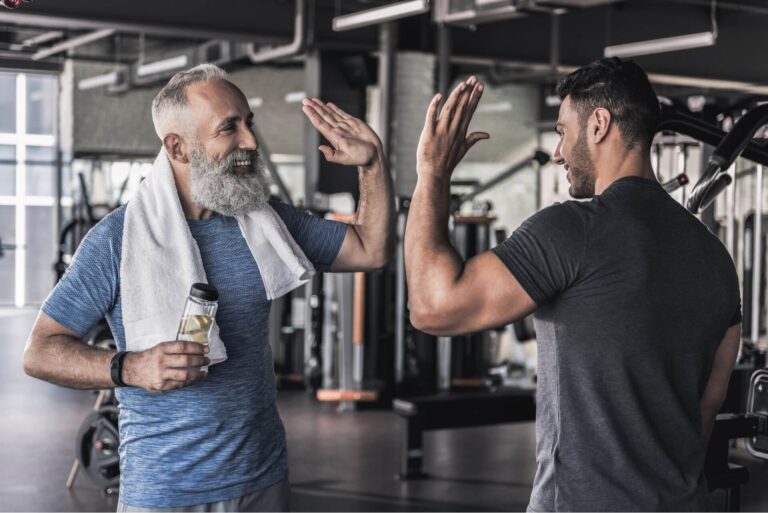 Cheerful males are talking to each other in modern gym