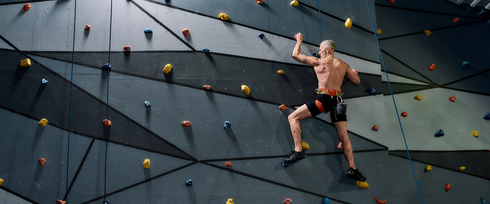 Middle aged shirtless man in safety equipment and harness training