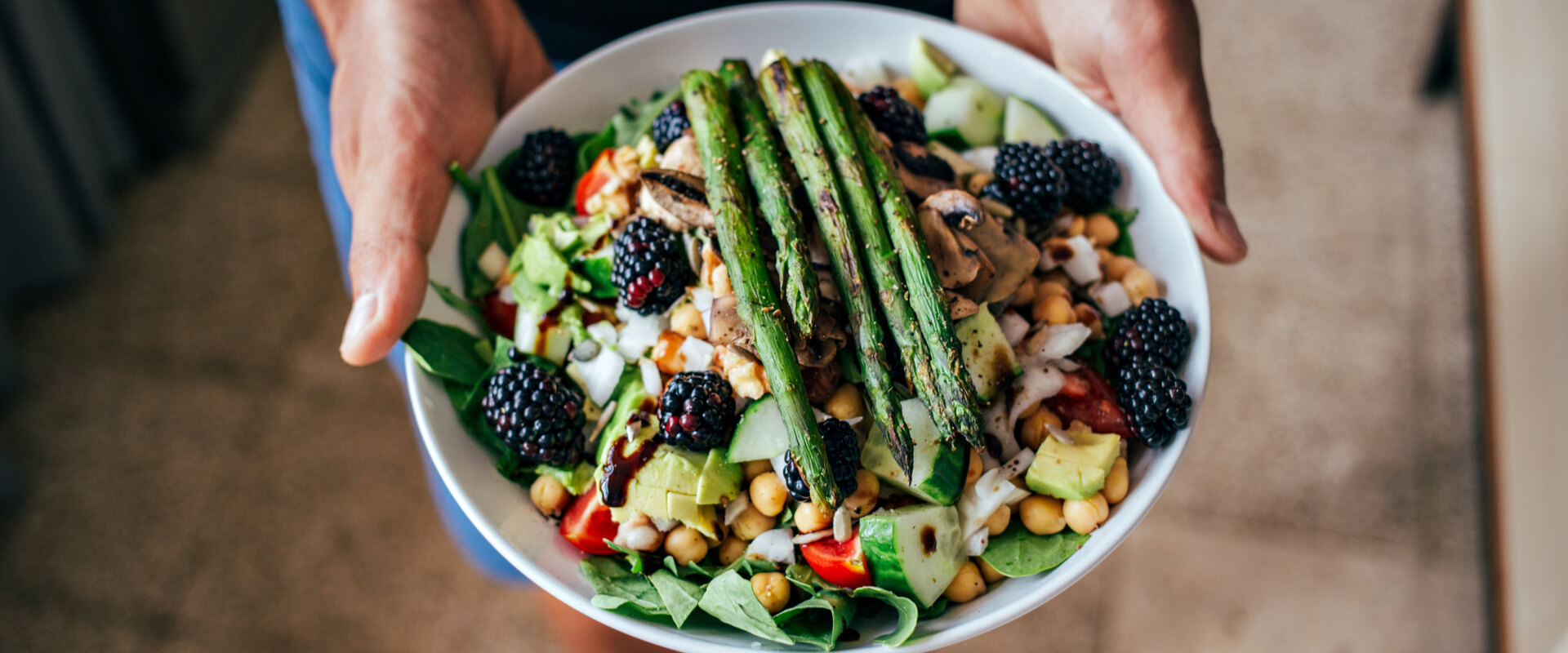 Man hands holding big deep plate full of healthy paleo vegetarian salad