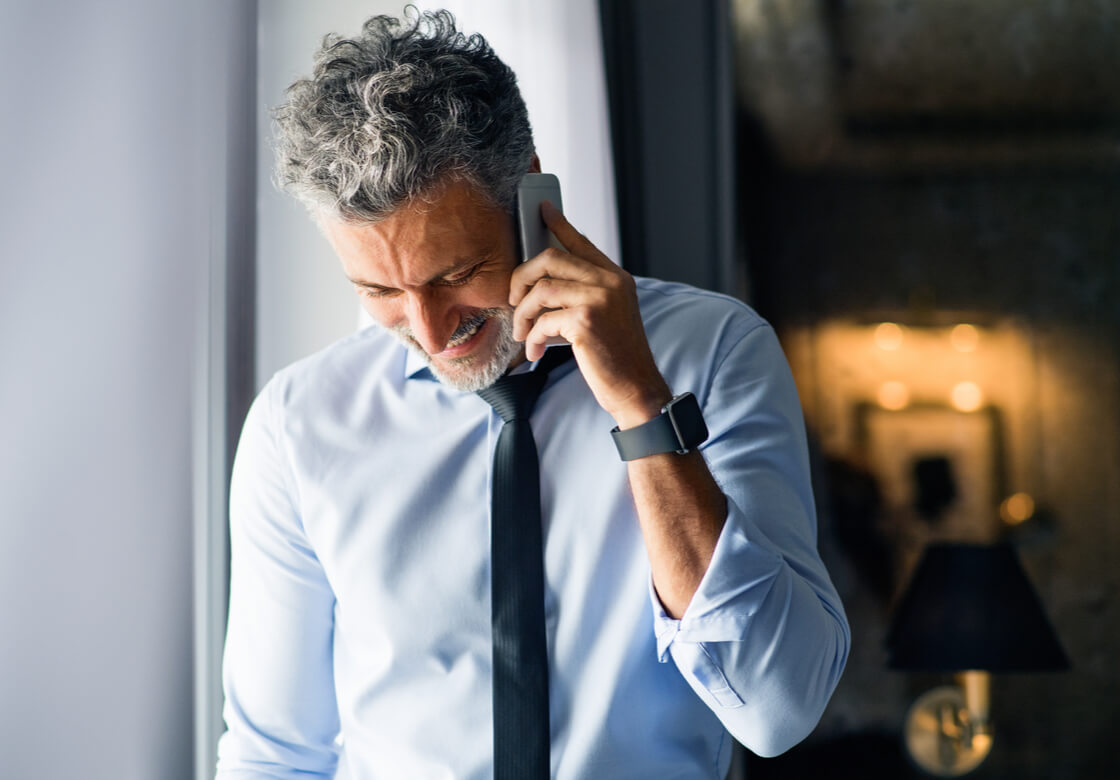 Mature businessman with smartphone in a hotel room.