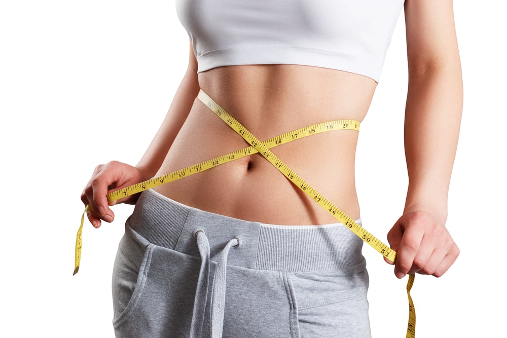 slim woman measuring her waist's size with tape measure.