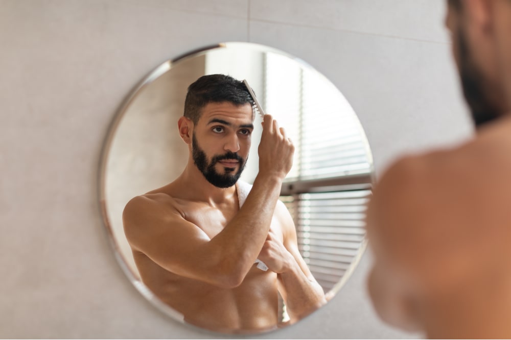 handsome young guy brushing his glossy hair