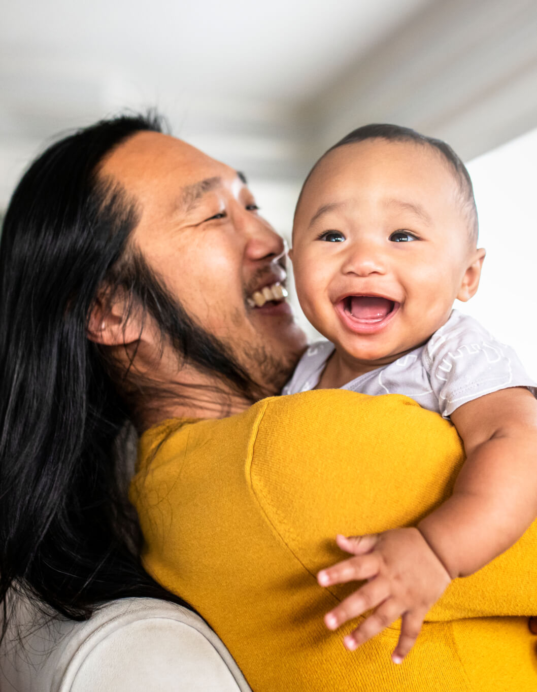 Asian American father hugging his little son