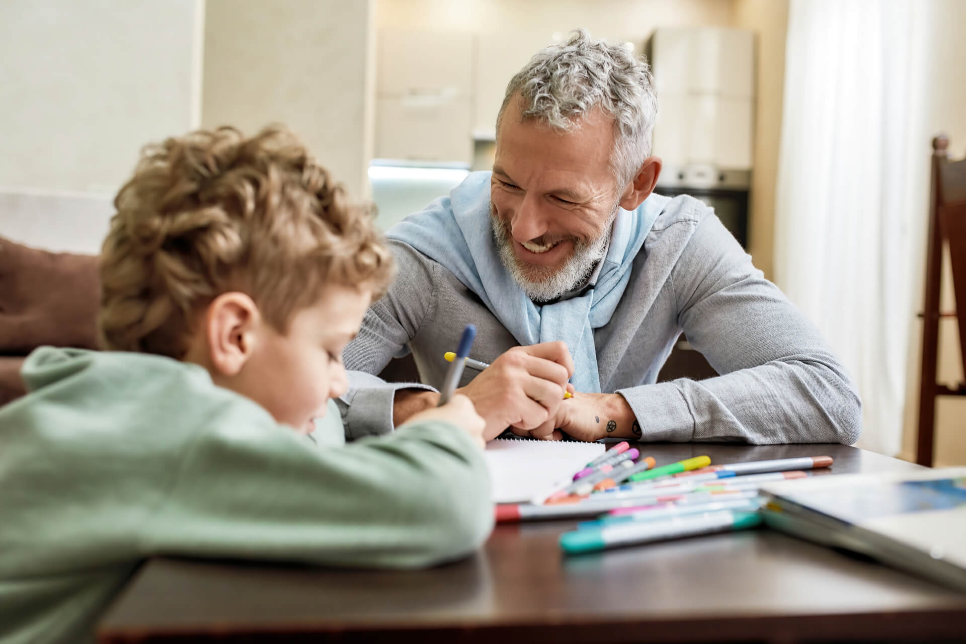 Happy grandfather and grandson sitting at table,