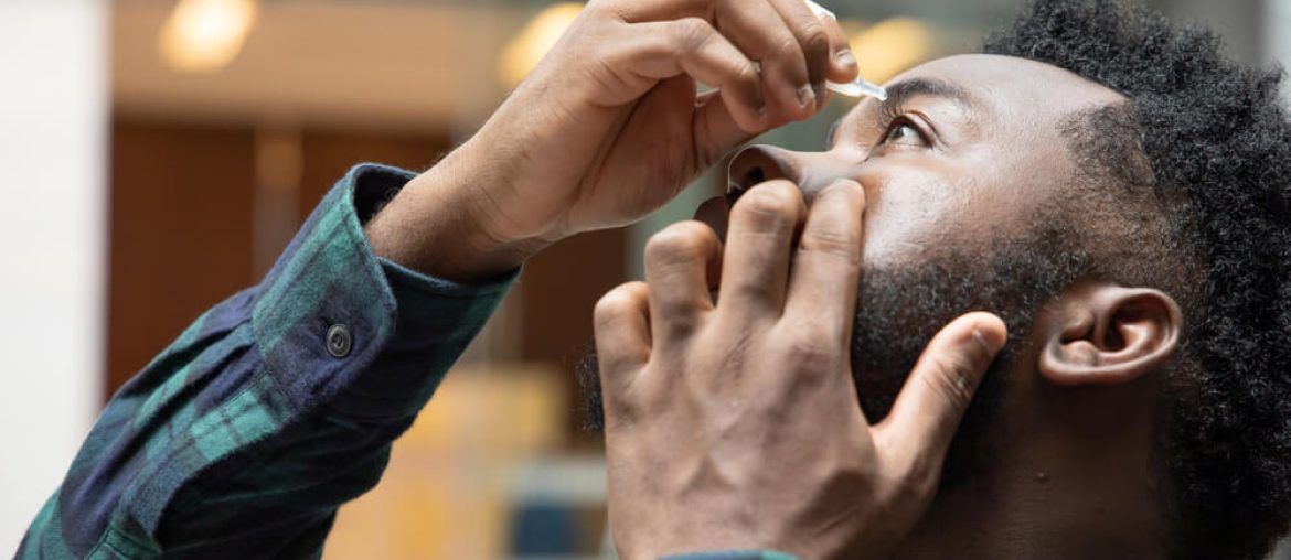 African man using eye drop, eye lubricant to treat dry eye or optical allergy