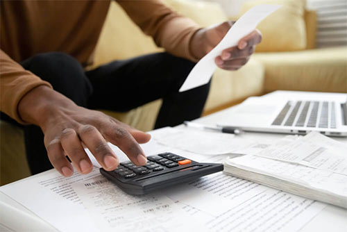 Someone looking at documents and using a calculator.