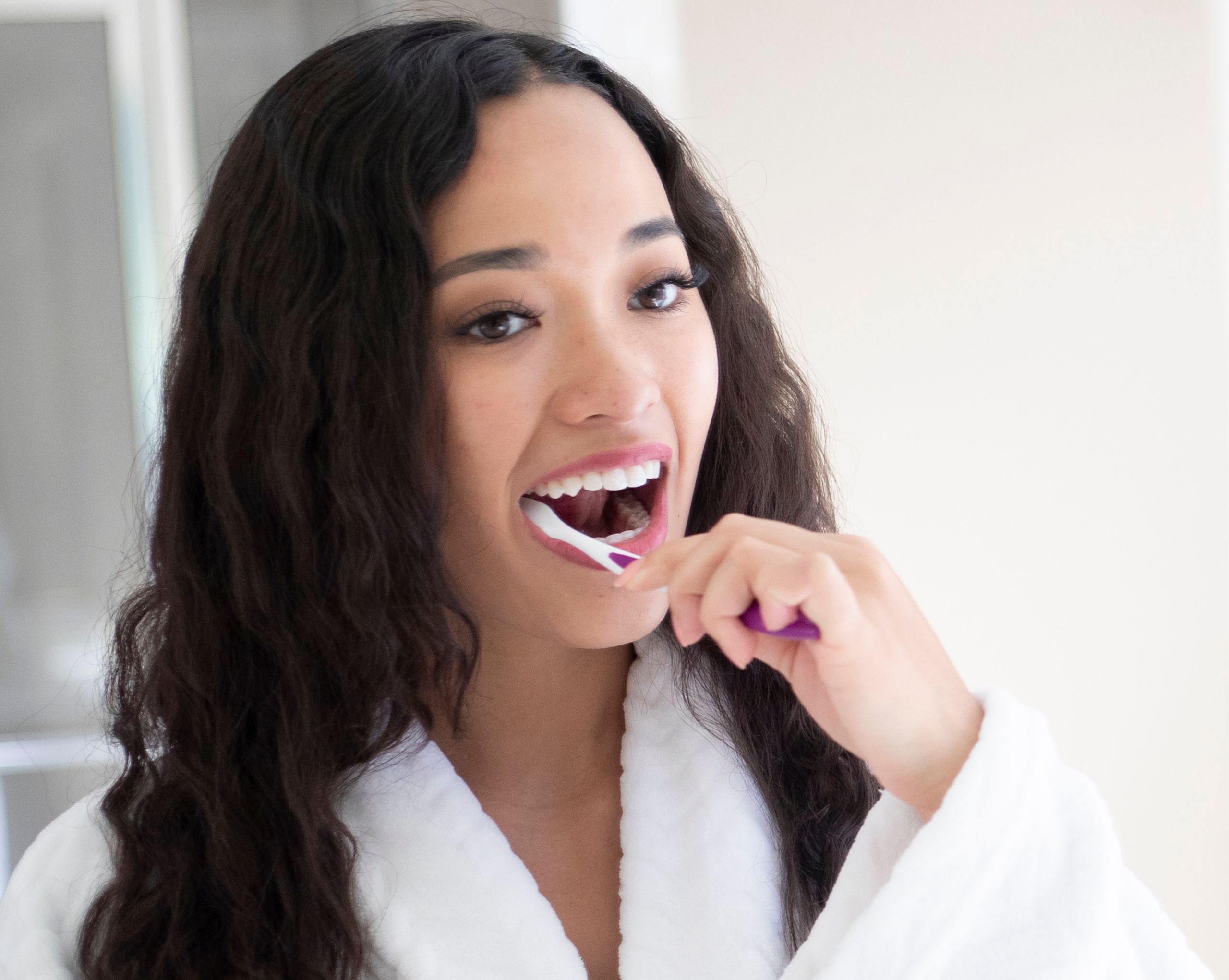 Young dark haired woman brushing her teeth