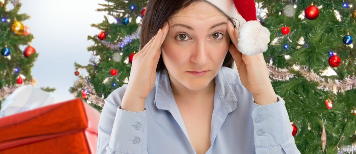 Stressed looking woman in a Santa hat in front of a Christmas tree
