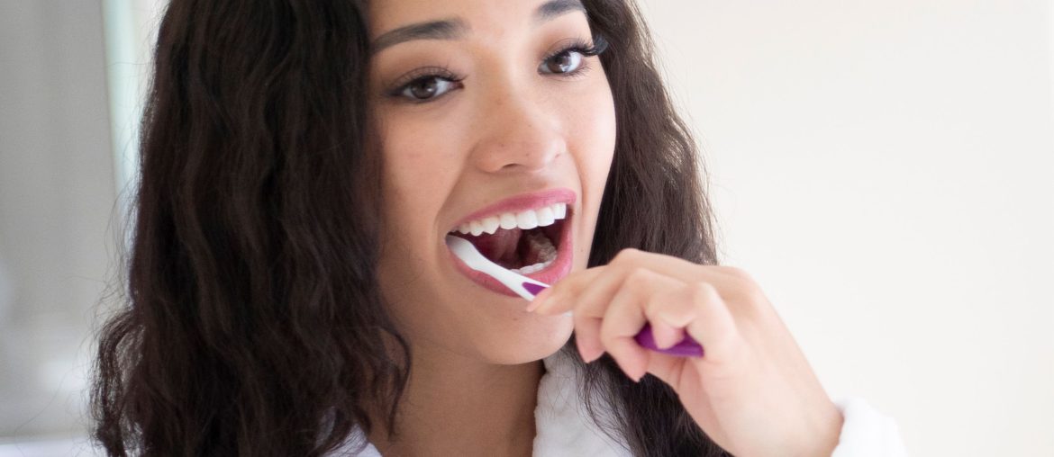Young dark haired woman brushing her teeth