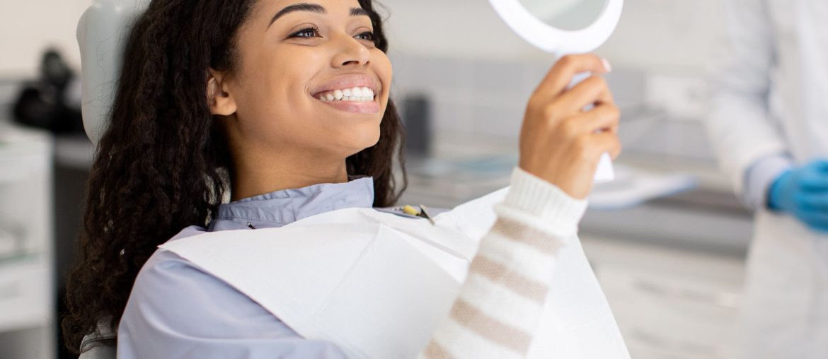 Young woman in dental chair admiring her new smile in a mirror