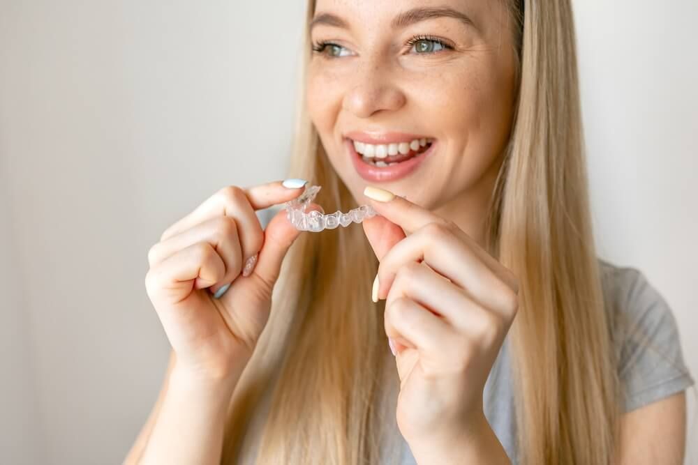 Smiling woman with healthy teeth using removable clear braces
