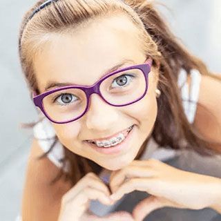 Little girl with braces making heart from hands