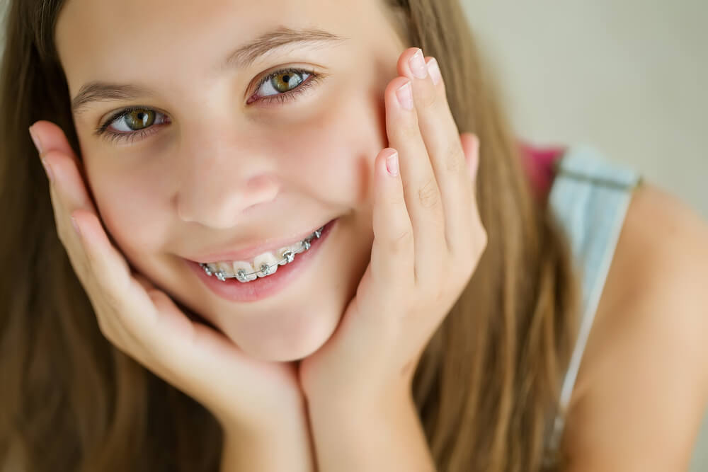 Cute kid with dental braces smiling.