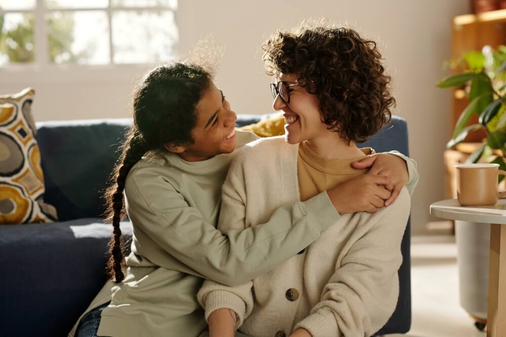 happy teenage girl embracing her foster mom while they spending time together