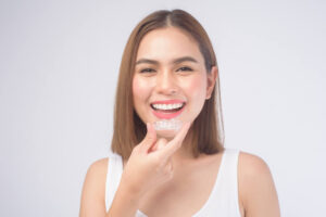 A young smiling woman holding invisalign braces