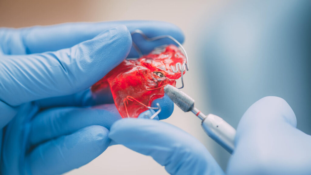 hands of a dentist doing correction on mobile denture.