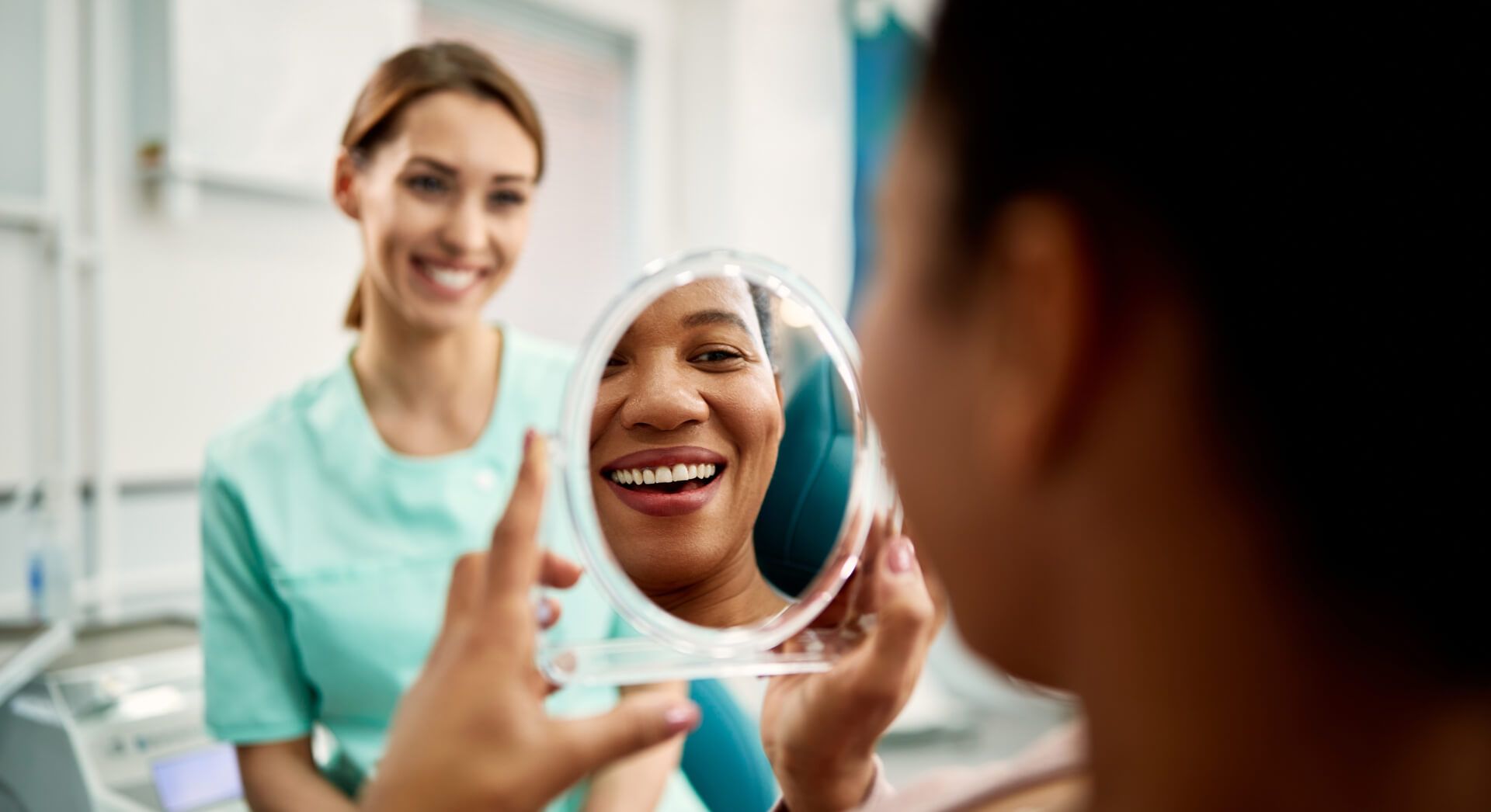 Woman using mirror while looking at her teeth after dental check up