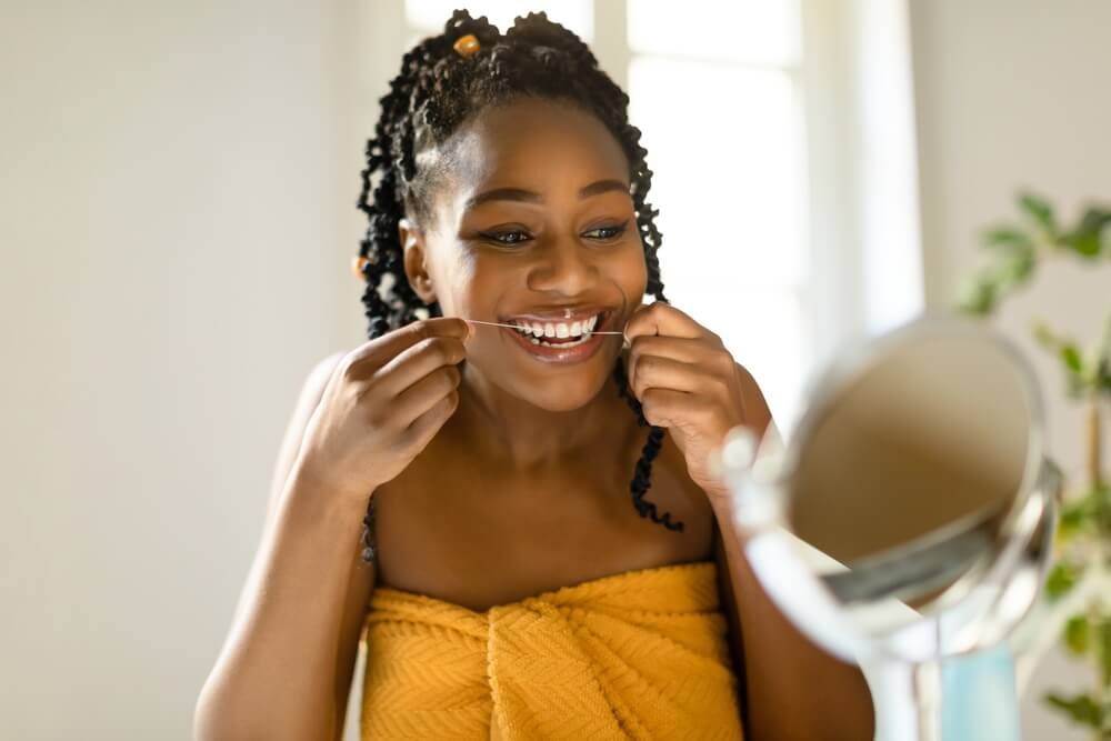 Woman looking at mirror and using dental floss
