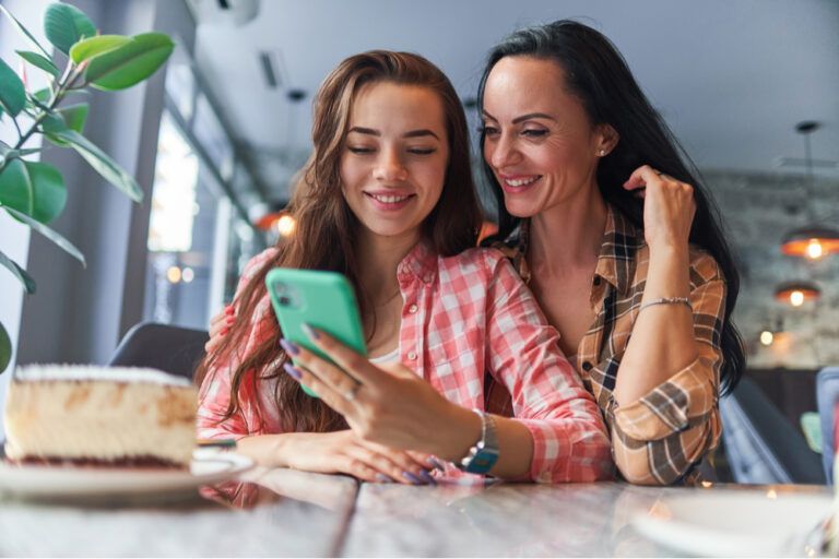 teenager daughter watching video content on the phone and having good time together