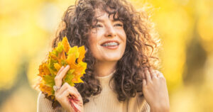 Young woman full of emotions from autumn season. Girl with a dental braces and curly hair.